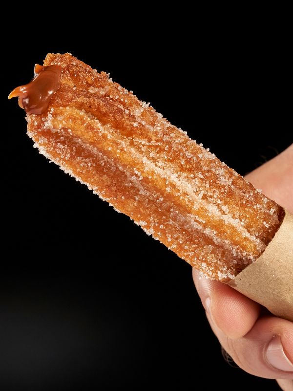 closeup with Dulce de leche churros held in hand
