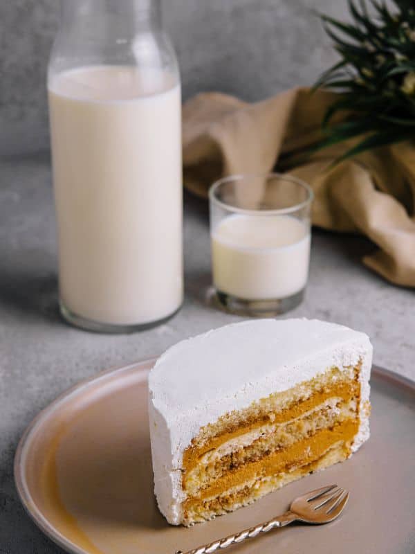 Dulce de leche layer cake on a plate and a bottle of milk next to it
