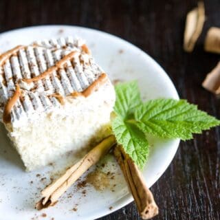 Tres Leches Cake with Dulce de Leche on a plate decorated with cinnamon sticks