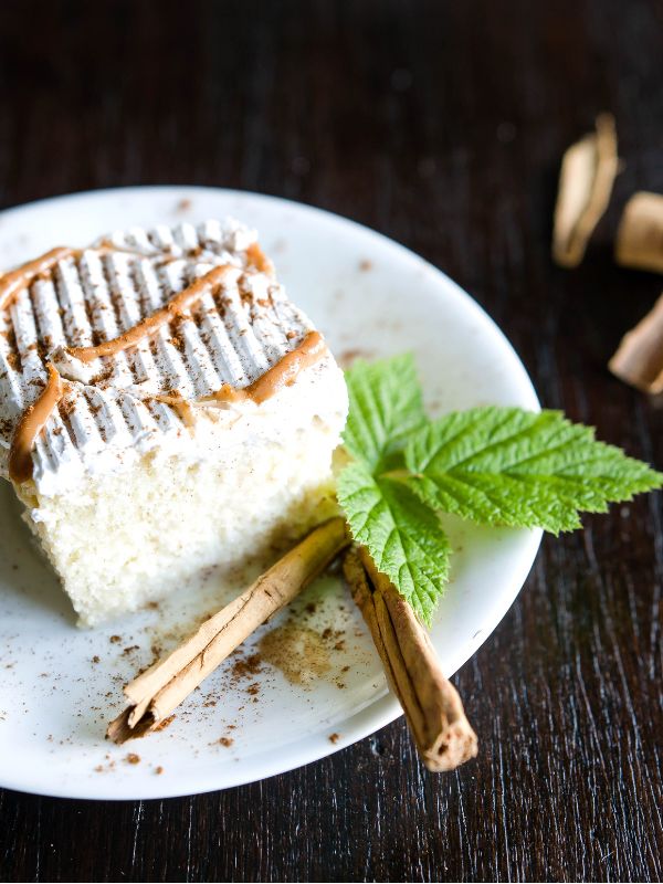 Tres Leches Cake with Dulce de Leche on a plate decorated with cinnamon sticks