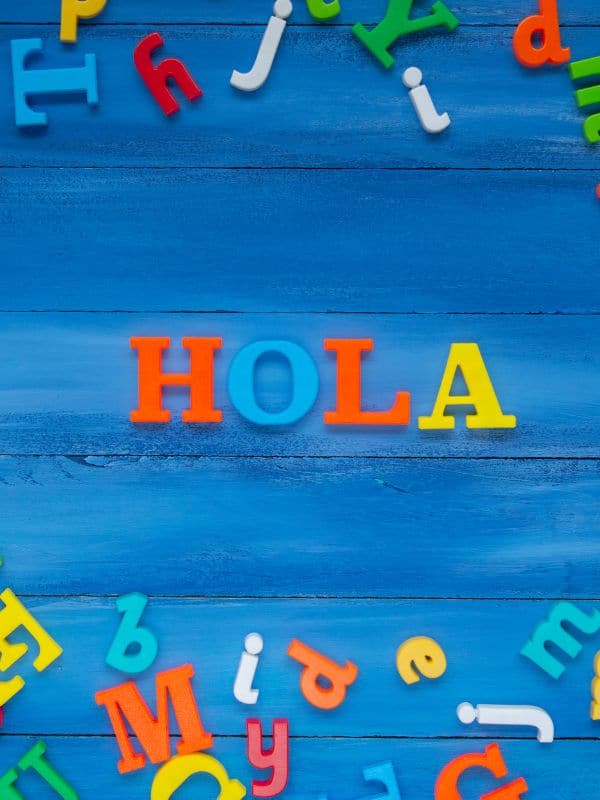colorful letter and the word hola on a blue font to learn Spanish for travel